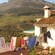 Ropa lavada colgada en una soga junto a una casa y una cubierta con vista a un huerto, valles y montañas